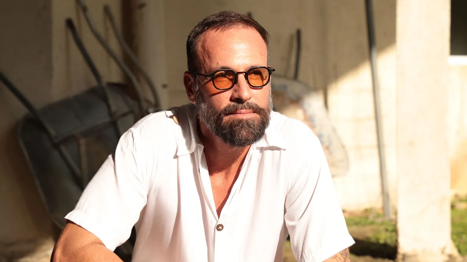 Vini Cavalieri de óculos de lentes alaranjadas e camisa branca, sob luz de fim de tarde