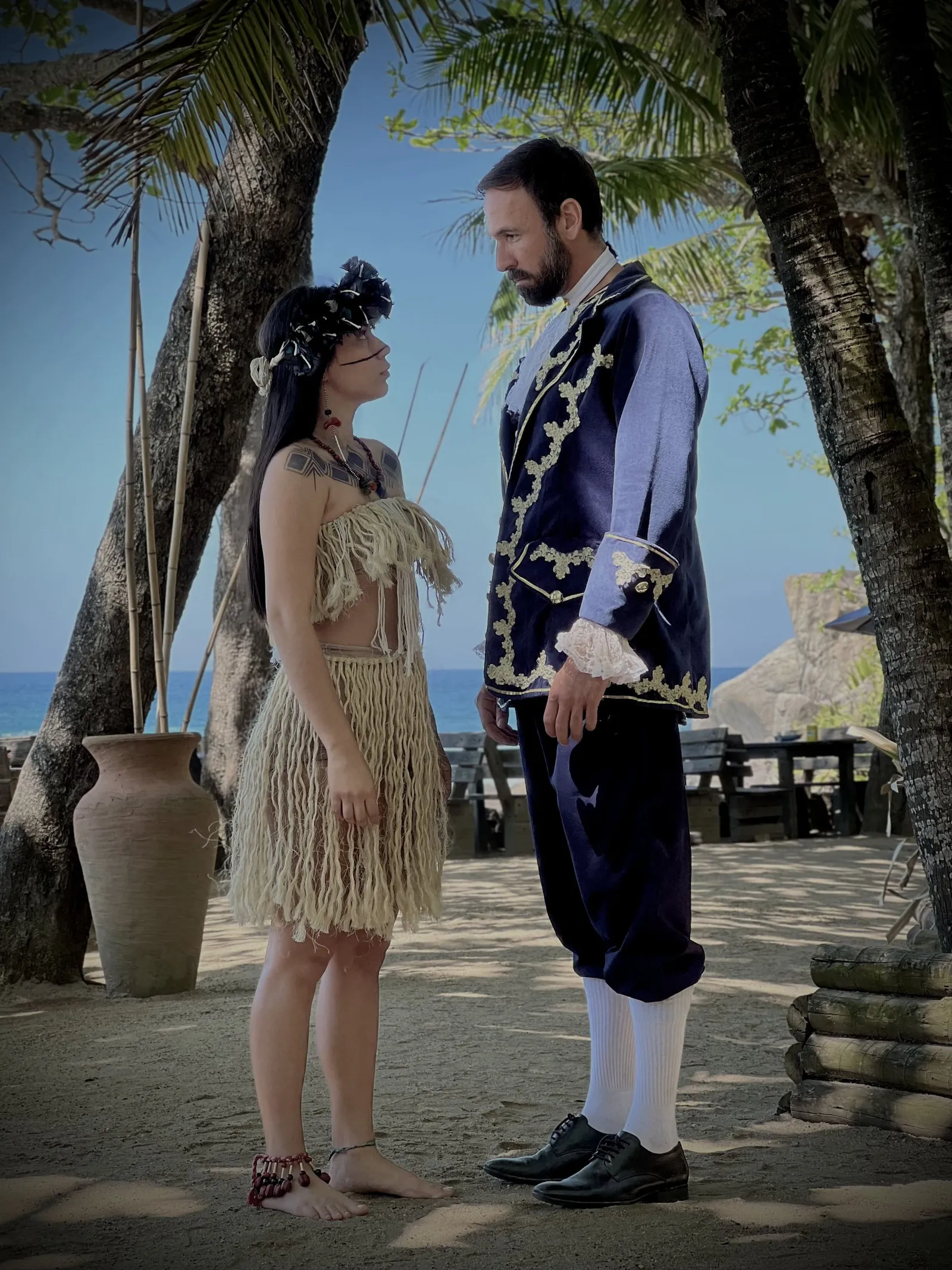 Vini Cavalieri com figurino de época, numa cena na praia ao lado de uma atriz